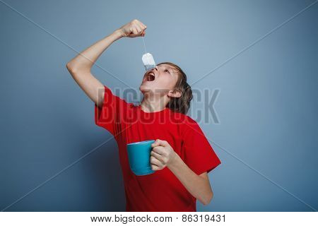boy teenager European appearance in a red shirt lowers the tea b