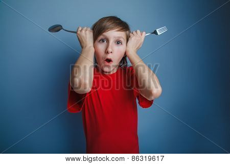 boy teenager European appearance in a red shirt put fork and spo