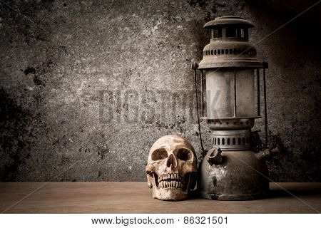 still life with skull human and old hurricane lamp
