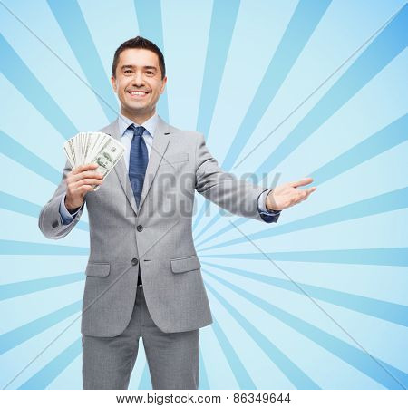 business, people and finances concept - smiling businessman with american dollar money over blue burst rays background