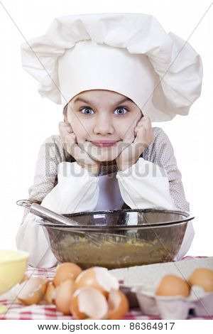 Little girl in a white apron breaks near the plate with eggs, isolated on white background