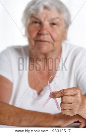 Elder Woman Holding Pink Breast Cancer Awareness Ribbon In Hand