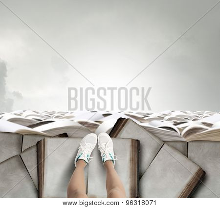 Close up of woman legs standing on the edge of rock of books 