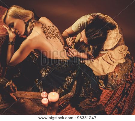 Drawing process of henna menhdi ornament on woman's back 