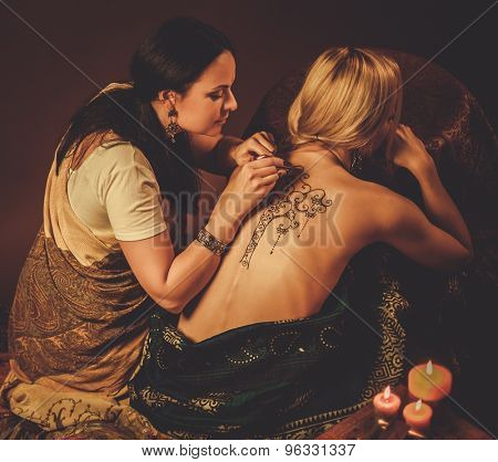 Drawing process of henna menhdi ornament on woman's back 