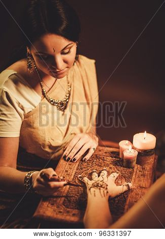 Drawing process of henna menhdi ornament on woman's hand 