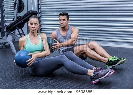 Portrait of muscular couple doing abdominal ball exercise