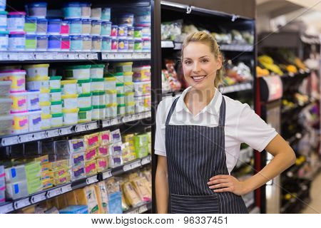 Portrait of a smiling blonde worker with hand on hip in supermarker