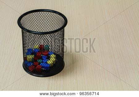 Paper tack in black basket on the wood background.