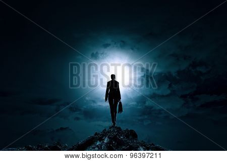 Rear view of businesswoman standing on top and looking in sky