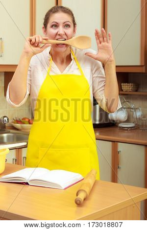 Cooking and preparing food meal concept. Thoughtful wondering and confused woman chef cook housewife holding biting ladle spoon in kitchen.
