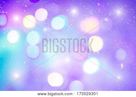 Defocused colorful ligths of Christmas tree. Multicolored bokeh lights during a snowfall. Background for greeting card. Winter composition. Happy holiday mood. Xmas and New Year fairy tale wallpaper.