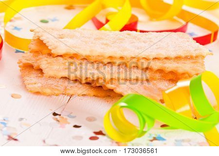 Carnival pastry with confetti on wooden table.
