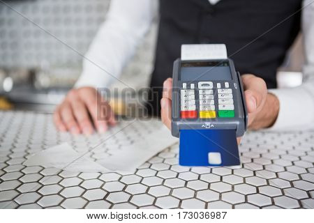 Bartender accepting a credit card at bar counter in bar