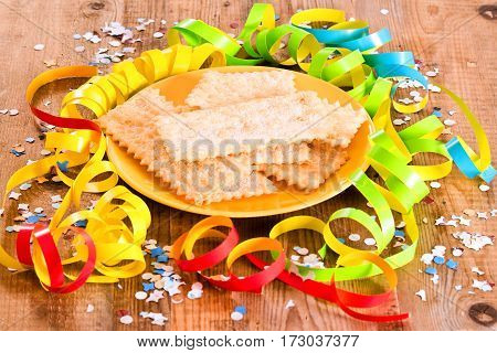 Carnival pastry with confetti on wooden table.