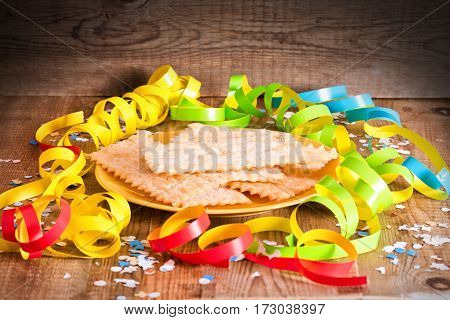 Carnival pastry with confetti on wooden table.