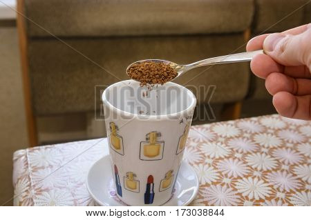 Hand with full spoon and glasses preparing instant coffee