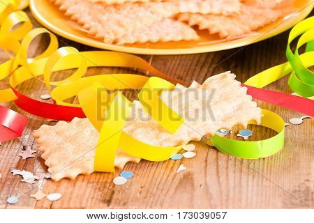 Carnival pastry with confetti on wooden table.