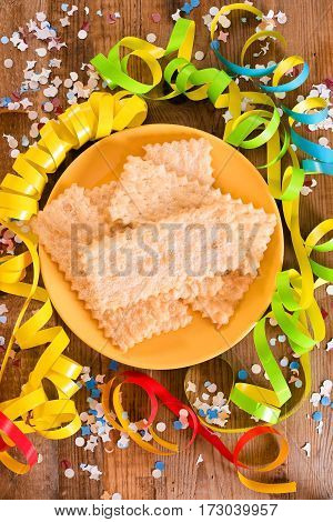 Carnival pastry with confetti on wooden table.