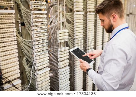 Technician using digital tablet while analyzing server in server room
