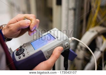 Mid section of technician using digital cable analyzer in server room