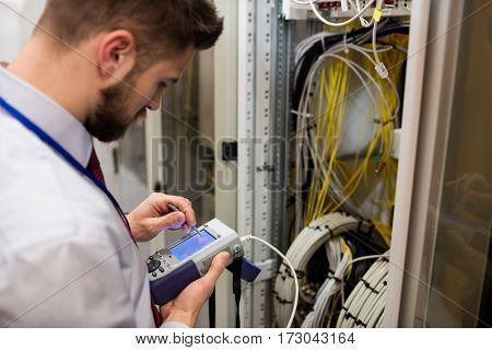 Technician using digital cable analyzer in server room