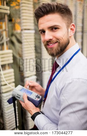 Portrait of technician using digital cable analyzer in server room