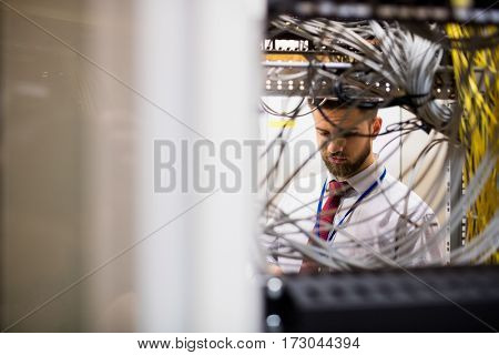 Technician checking cables in a rack mounted server in server room