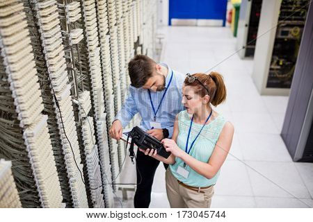 Technicians using digital cable analyzer in server room