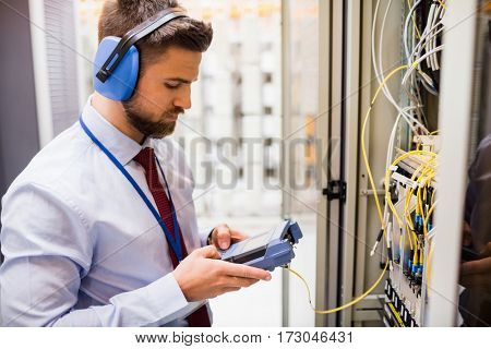 Technician using digital cable analyzer in server room