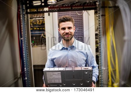 Portrait of technician removing server from rack mounted server in server room