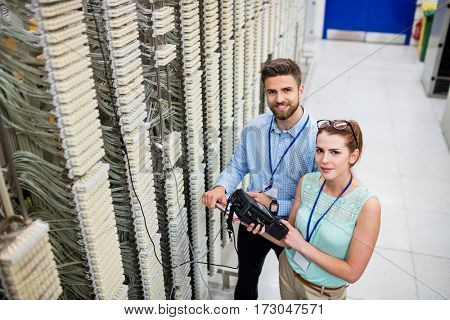 Portrait of technicians using digital cable analyzer in server room