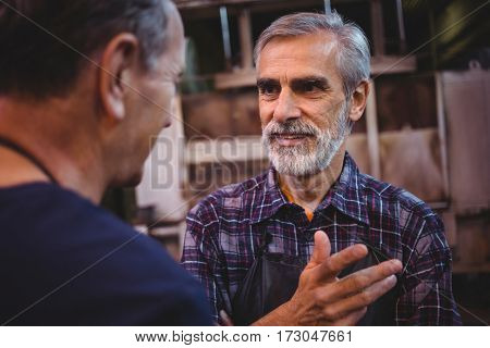 Glass blower interacting with each other at glass blowing factory
