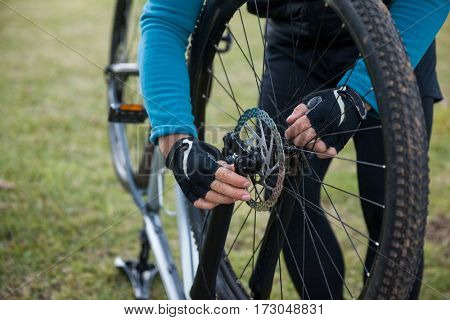Male mountain biker examining front wheel of his bicycle in the forest