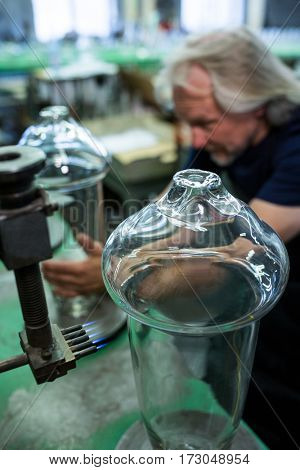 Glassblower working on a glass at glassblowing factory