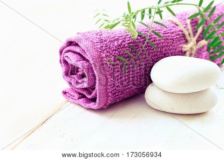 Relaxing spa background with empty space for product display. Violet bathroom towel, green plant decor, stones. Soft light.