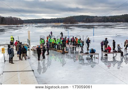 Group of ice skaters and volunteers at a rest area on the ice.Upplands Vasby, Sweden - February 19, 2017: Group of ice skaters and volunteers on melting ice lake late winter day seen from above. Participants and volunteers of the annual ice skating event 