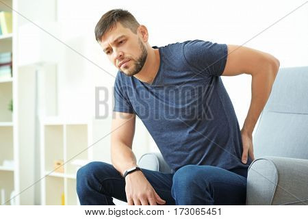 Handsome young man suffering from backache at home