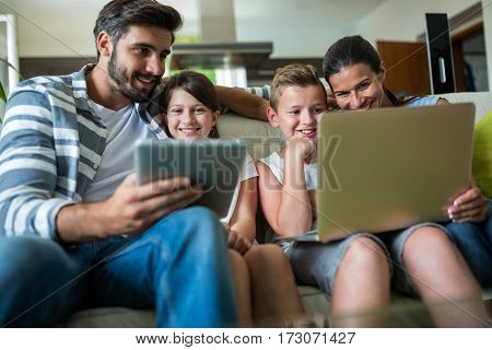 Happy family using laptop and digital tablet in the living room at home
