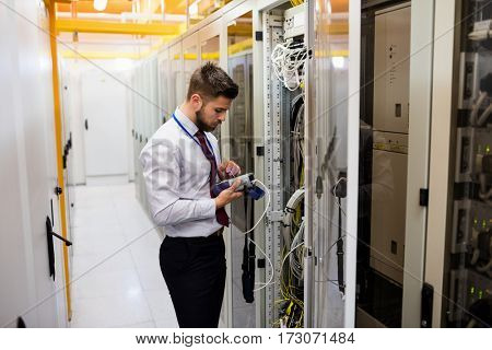 Technician using digital cable analyzer in server room