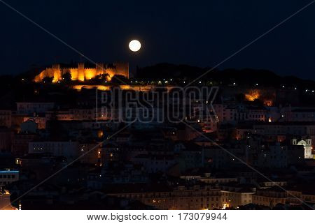 The lisbon castle during a huge full moon, seen from the opposite viepoint at bairro alto