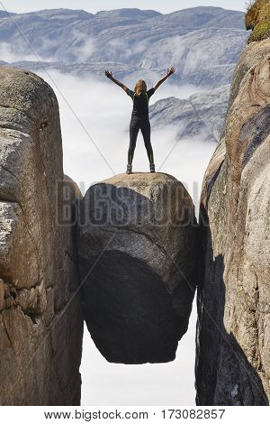 Norwegian fjord landscape. Woman hiker. Kjeragbolten landmark. Norway adventure tourism