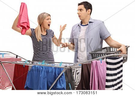Young couple having an argument while hanging clothes on a clothing rack dryer isolated on white background