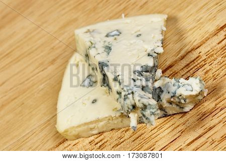 Blue cheese close up on an old wooden table and a knife horizontal macro mold