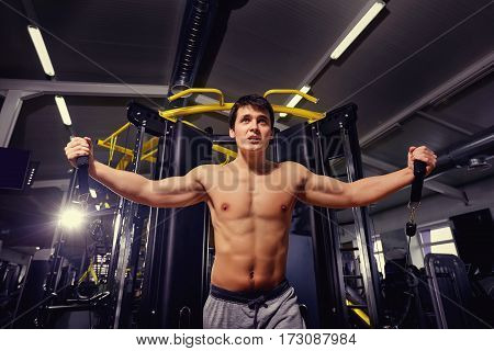 Man with a sports figure doing exercise on  simulator in the gym.