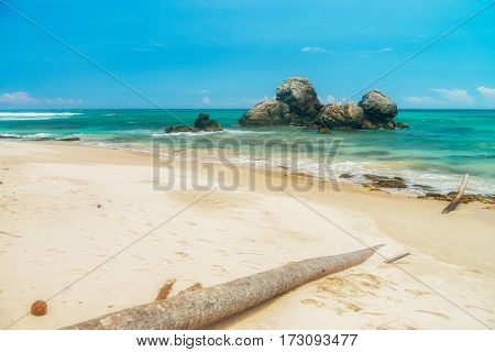 Sunny beach near Koggala - Sri Lanka The area famous for its distinct stilt fishermen, who erect a single pole in the chest-deep water on the beach, just few meters off-shore. Splittoned, vivid image.