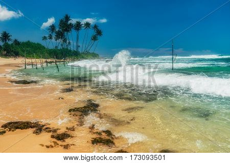 Sunny beach near Koggala - Sri Lanka The area famous for its distinct stilt fishermen, who erect a single pole in the chest-deep water on the beach, just few meters off-shore. Splittoned, vivid image.