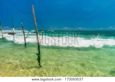 Sunny beach near Koggala - Sri Lanka The area famous for its distinct stilt fishermen, who erect a single pole in the chest-deep water on the beach, just few meters off-shore. Splittoned, vivid image.
