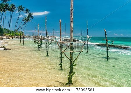 Sunny beach near Koggala - Sri Lanka The area famous for its distinct stilt fishermen, who erect a single pole in the chest-deep water on the beach, just few meters off-shore. Splittoned, vivid image.