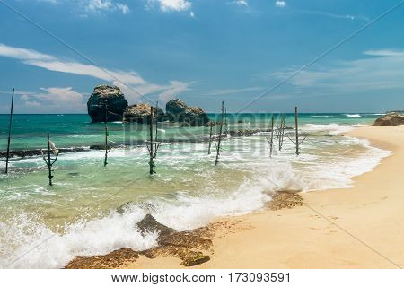Sunny beach near Koggala - Sri Lanka The area famous for its distinct stilt fishermen, who erect a single pole in the chest-deep water on the beach, just few meters off-shore. Splittoned, vivid image.